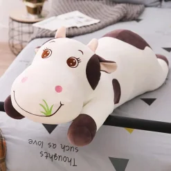 La compagnie de la peluche Peluche vache coloré qui broute de l'herbe